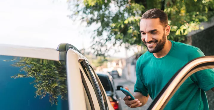 homem sorridentes entrando em seu carro.