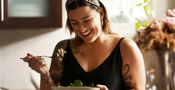 Mulher come uma salada na copa da empresa