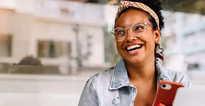 mulher sorrindo com celular na mão.