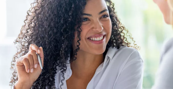mulher sorrindo enquanto explica algo para outra.