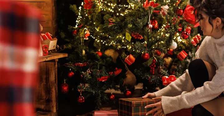 mulher pegando presente sob uma árvore de natal.