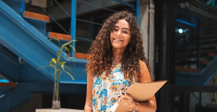 estagiária sorrindo enquanto segura documentos.