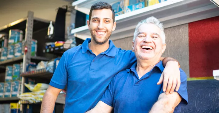 dois homens de diferentes idades sorrindo no trabalho.