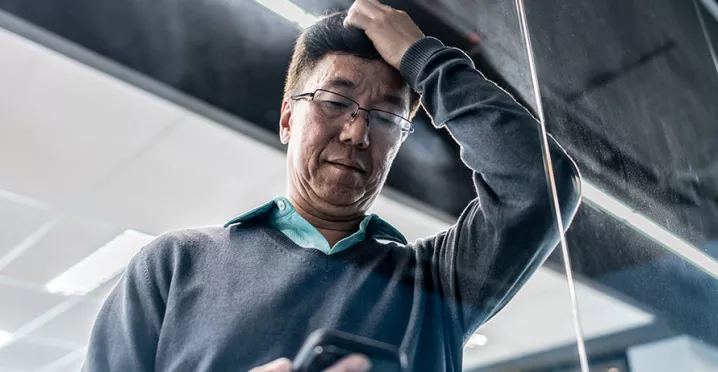 pessoa olhando o celular no trabalho com expressão de preocupação.