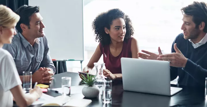 4 pessoas discutindo algo em mesa de reunião.