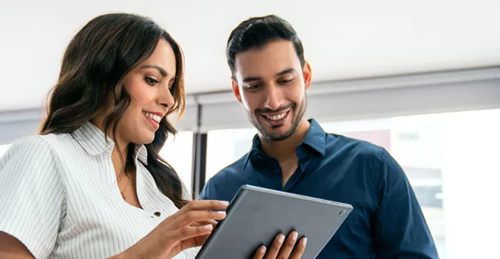 uma mulher e um homem olhando para algo em um tablet.