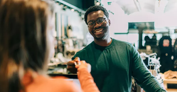 homem pagando compras enquanto sorri.