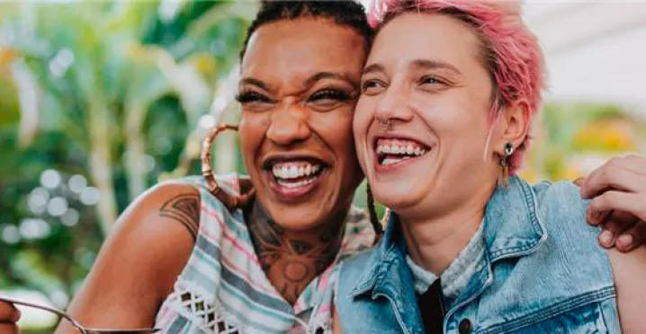 Imagem mostra duas mulheres abraçadas sorrindo e comendo felizes