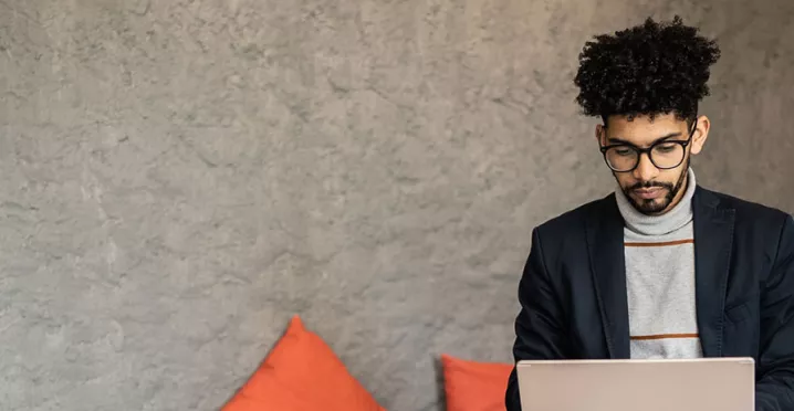 homem trabalhando com laptop no colo e semblante sério.