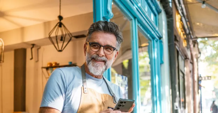 A imagem mostra um homem usando avental na frente de um estabelecimento