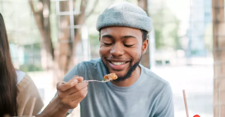 A imagem mostra um rapaz e uma mulher se alimentando ao ar livre
