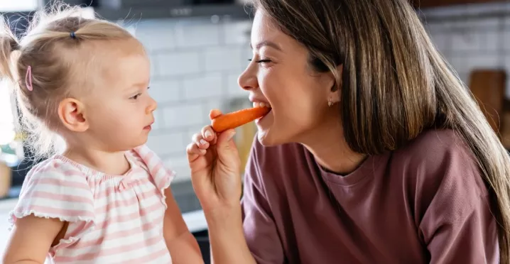 A imagem mostra uma mulher e uma criança comendo frutas