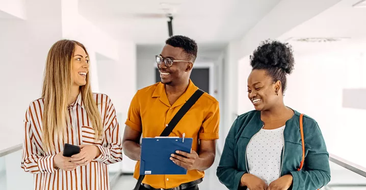 três pessoas conversando e rindo em corredor.