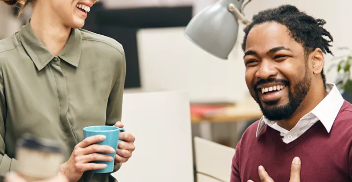 pessoas sorrindo e conversando em ambiente corporativo.