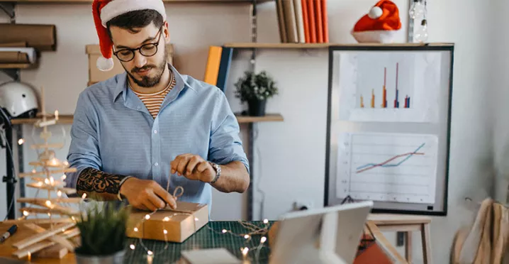 Funcionário em home office desembala um presente de Natal da empresa