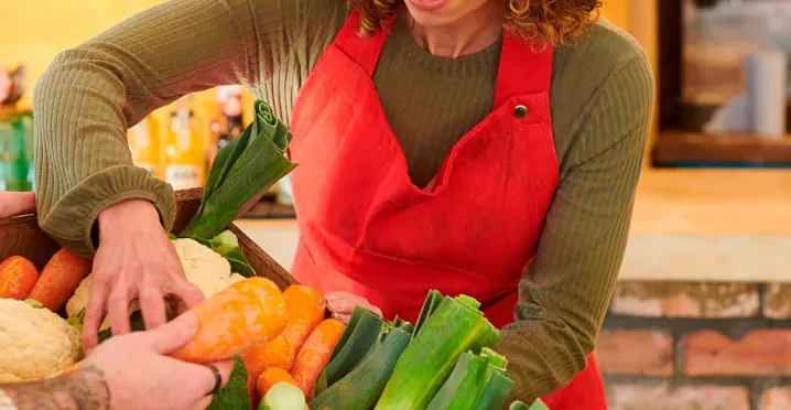 foto mostra duas pessoas mexendo em uma cesta de legumes frescos