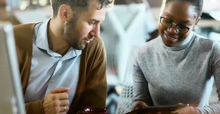 duas pessoas conversando enquanto olham algo em tablet.