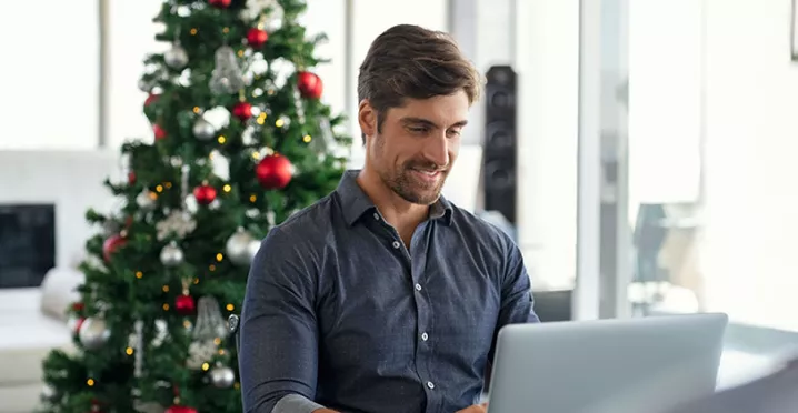 homeme trabalhando com árvore de natal atrás.
