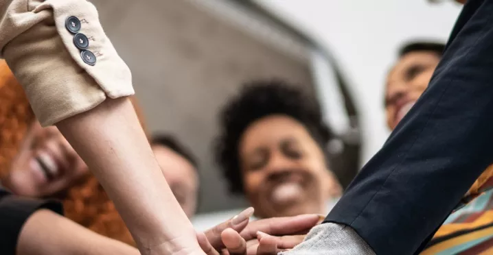 A imagem mostra um grupo de trabalhadores juntando as mãos e celebrando