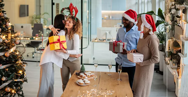 pessoas trocando presentes de natal em escritório.