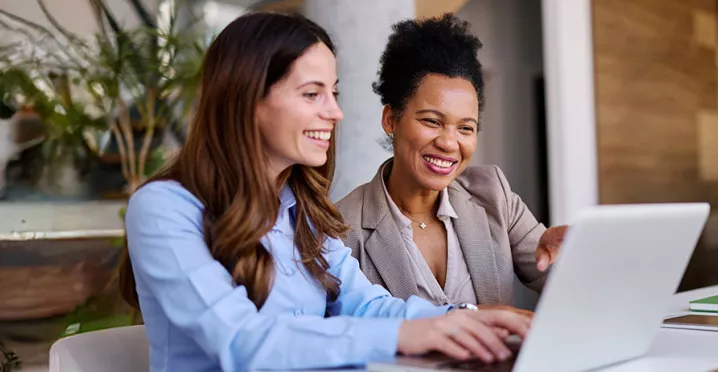 duas mulheres sorrindo para notebook.