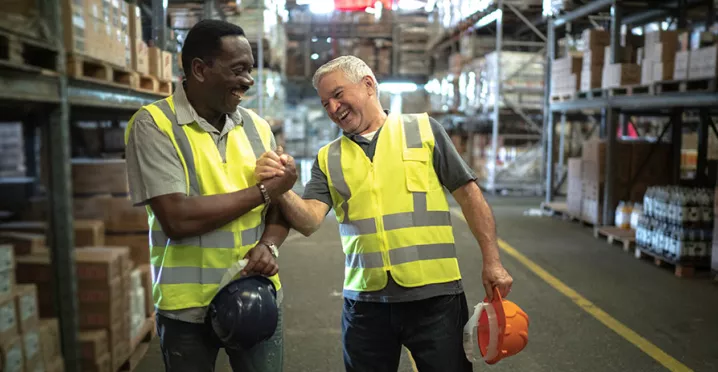 Foto mostra dois funcionários de uma empresa comemorando os resultados do final de ano