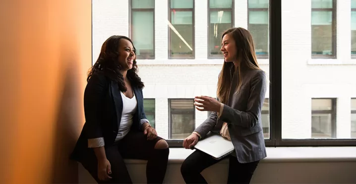 Foto mostra duas pessoas conversando em uma sala de reunião