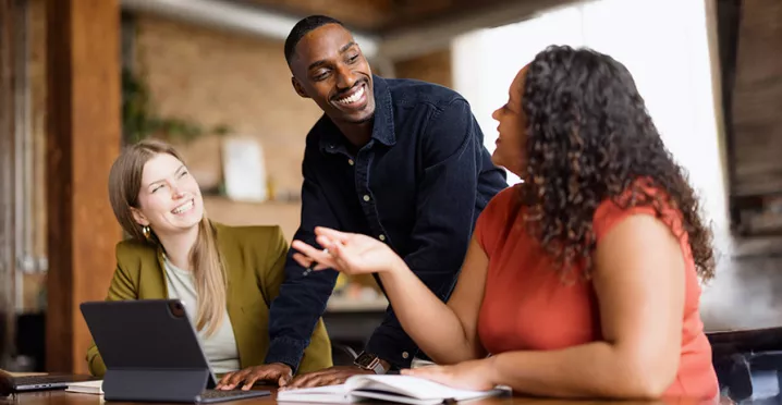 Três colegas de trabalho conversam animadamente durante uma reunião
