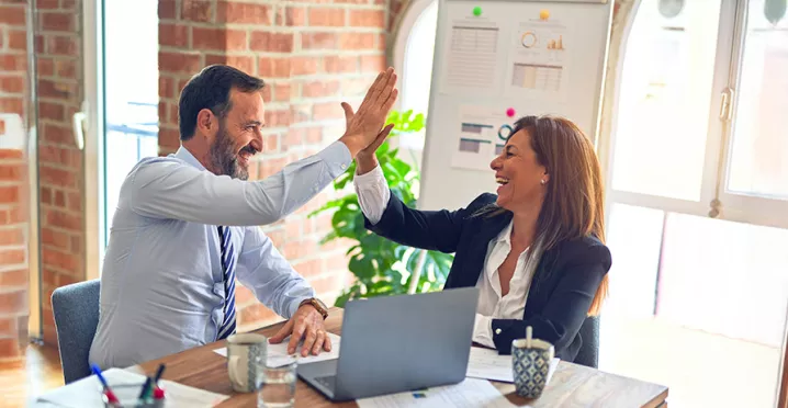 duas pessoas fazendo "toca aqui" no trabalho.