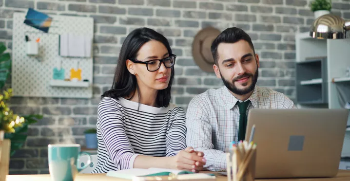 Foto mostra um chefe trabalhando uma pessoa de sua equipe