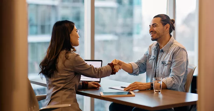 duas pessoas dando um aperto de mãos em escritório.