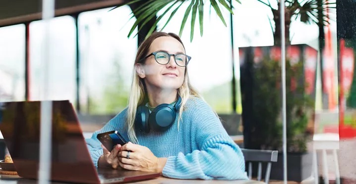Foto mostra uma pessoa trabalhando em um notebook em uma sala ampla