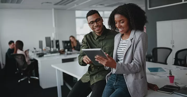 duas pessoas olhando informação em tablet no escritório.