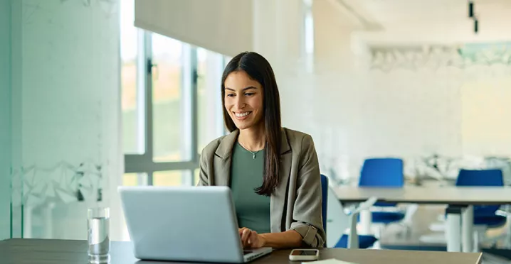 mulher sorrindo enquanto usa o computador no trabalho.