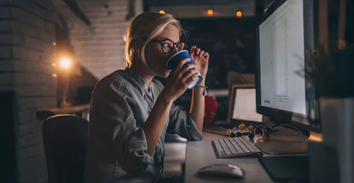 pessoa tomando chá enquanto trabalha à noite.