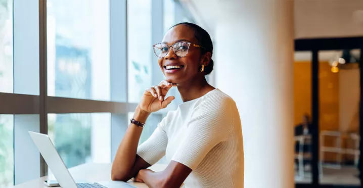 Foto mostra uma mulher animada no seu local de trabalho