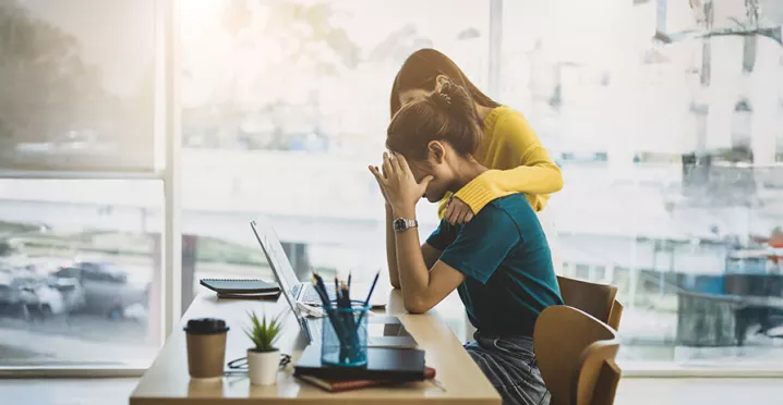 uma mulher oferecendo apoio para outra, que está preocupada com o trabalho.