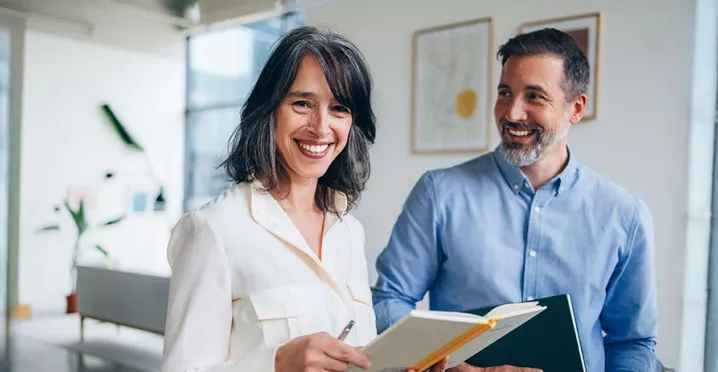 duas pessoas sorrindo no ambiente de trabalho.