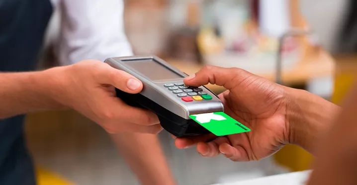 Foto mostra uma pessoa pagando sua conta com um cartão Pluxee