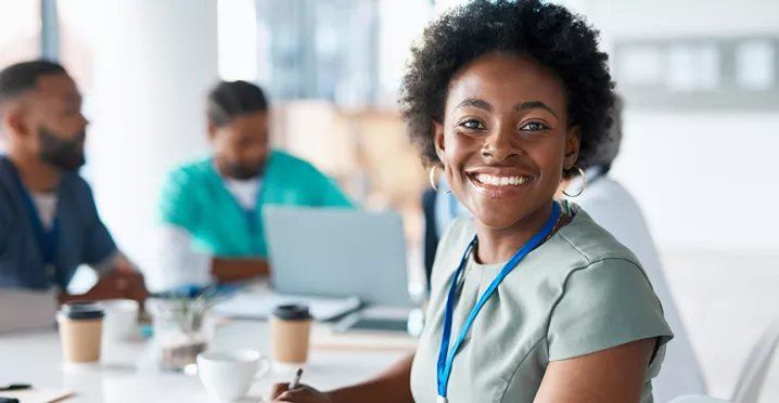 profissional da saúde sorrindo para a câmera rodeada por colegas.