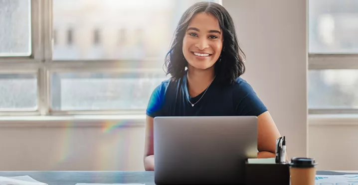 mulher sorrindo para a câmera enquanto usa notebook.