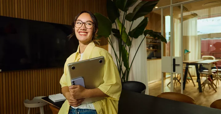 mulher sorrindo enquanto segura notebook.