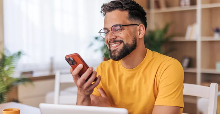 homem sorrindo para algo no celular.