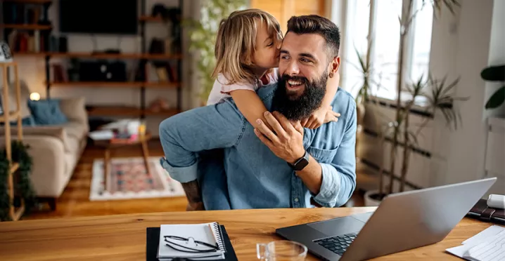 Foto de um homem brincando com sua filha durante um dia de home office