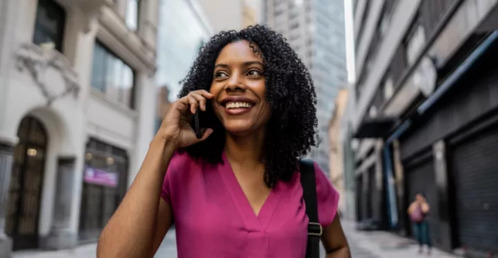 mulher negra, segurando o celular e sorrindo