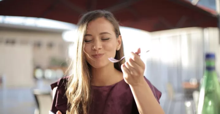 mulher sorrindo com um garfo na mão 