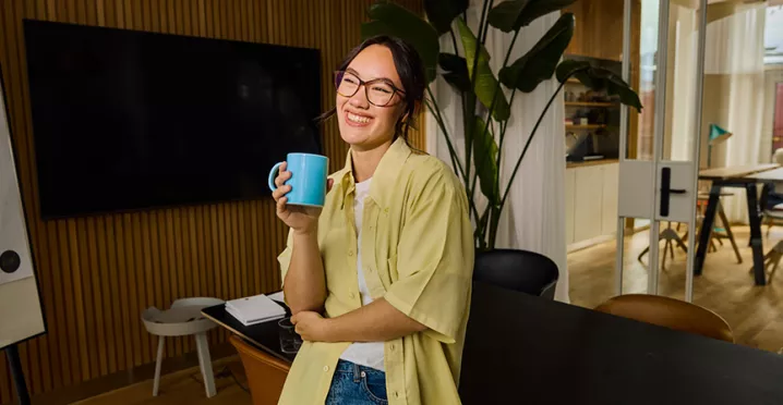mulher sorrindo enquanto bebe algo em caneca.