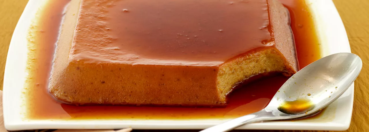 uma travessa braca com servindo um pudim de banana com cobertura caramelizada 