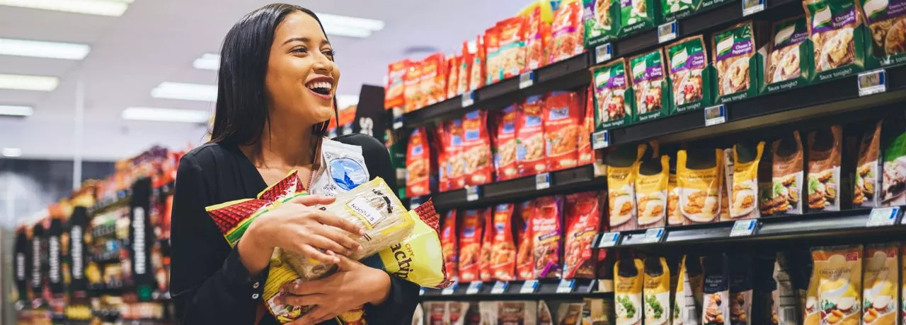 Mulher se diverte fazendo compras no supermercado com seu vale-alimentação