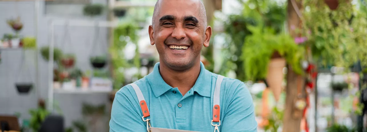 Pequeno empreendedor sorri no seu estabelecimento comercial